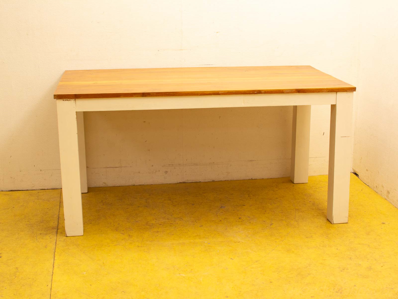 Minimalist wooden table with white legs on a vibrant yellow floor, perfect for any setting.