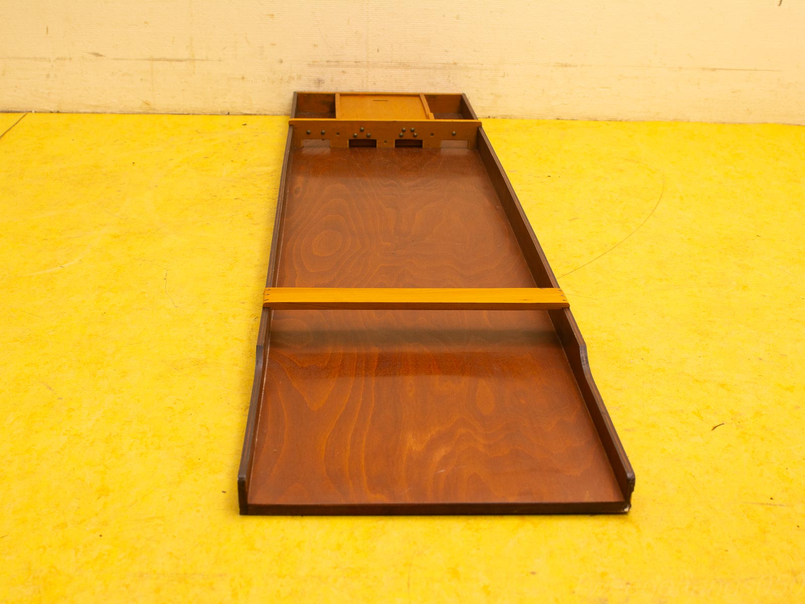 Elegant wooden organizer on a vibrant yellow surface, blending functionality and contemporary style.