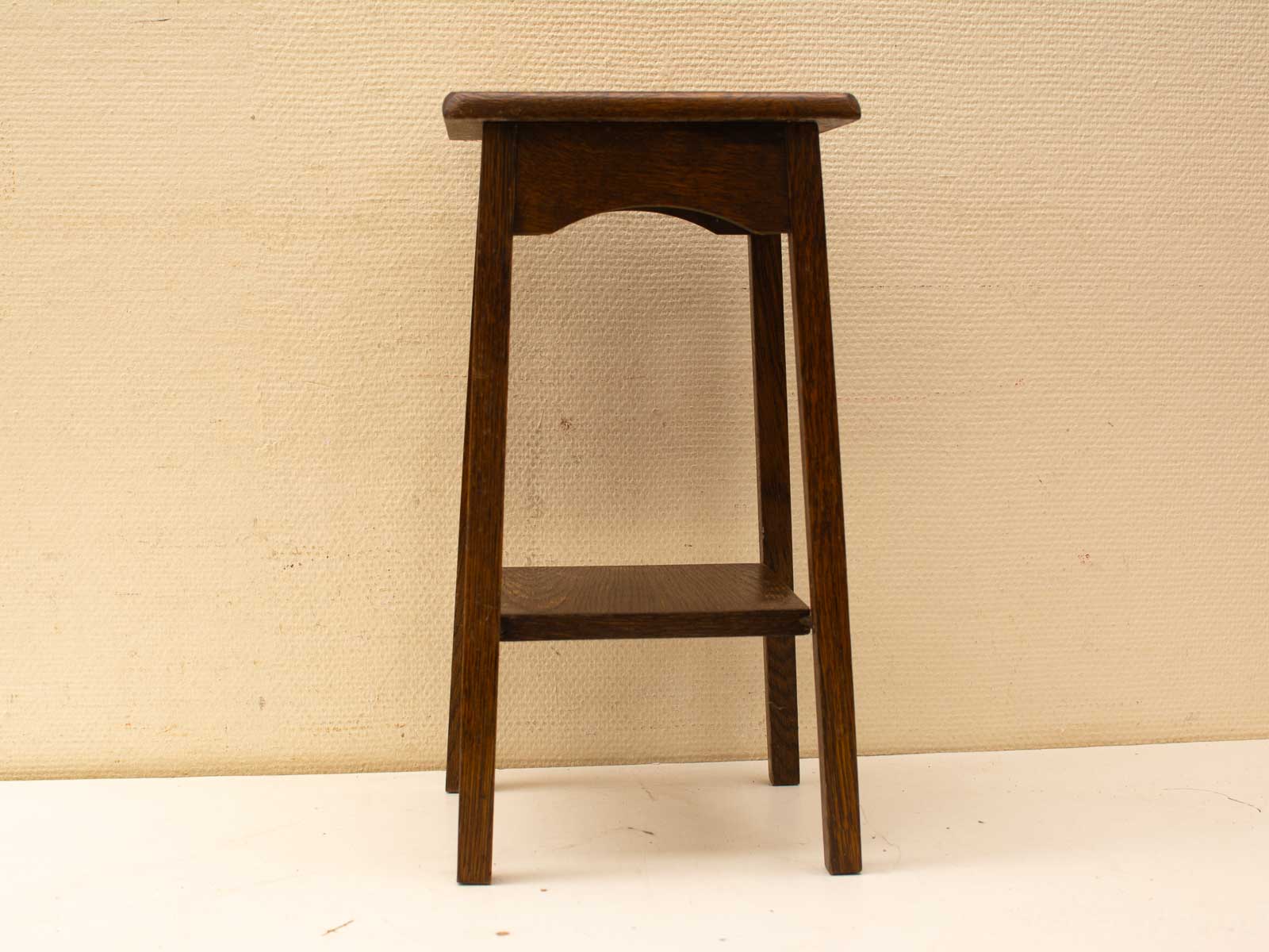 Elegant dark wood stool with storage shelf, perfect for seating or display in any space.