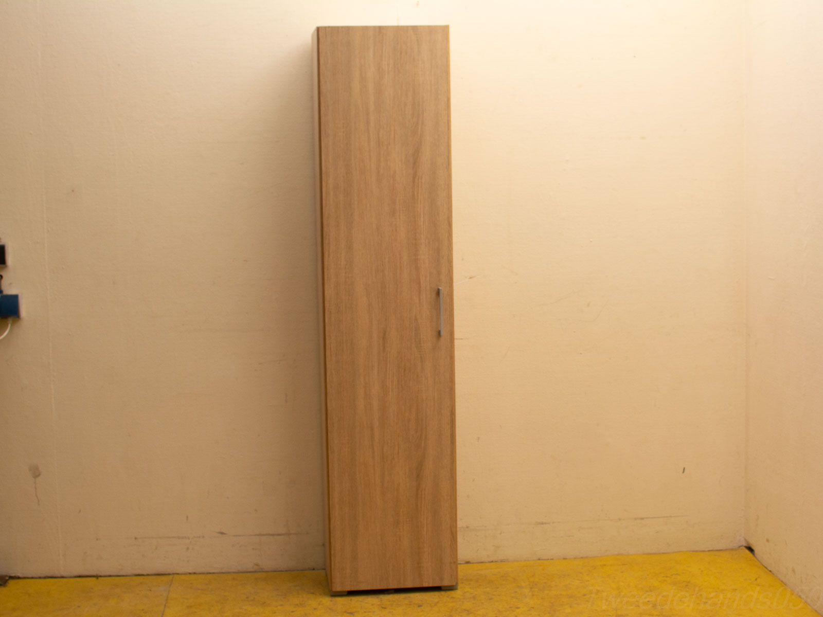 Sleek wooden cabinet with silver handle against light wall and vibrant yellow floor.