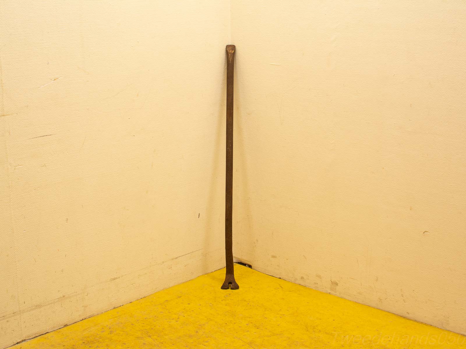 Rustic wooden stick in a corner, contrasting with cream walls and vibrant yellow floor.