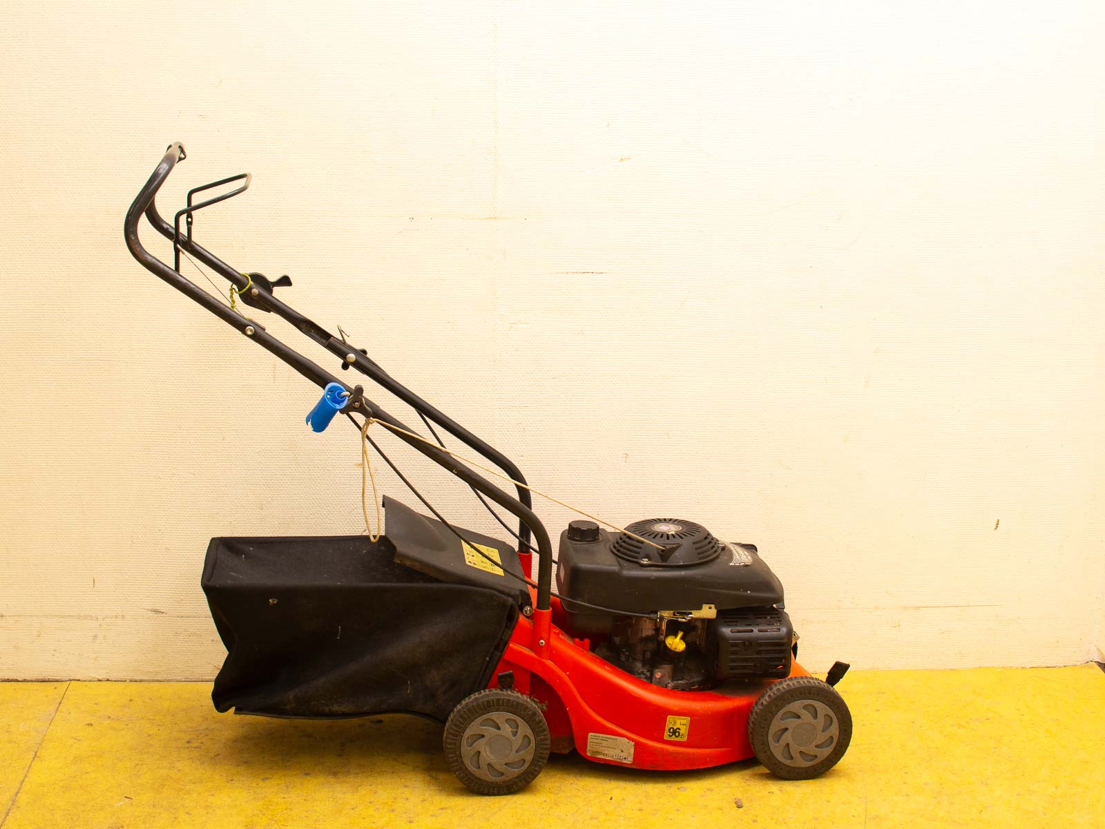 Compact red lawn mower with grass bag for efficient lawn care and maintenance.