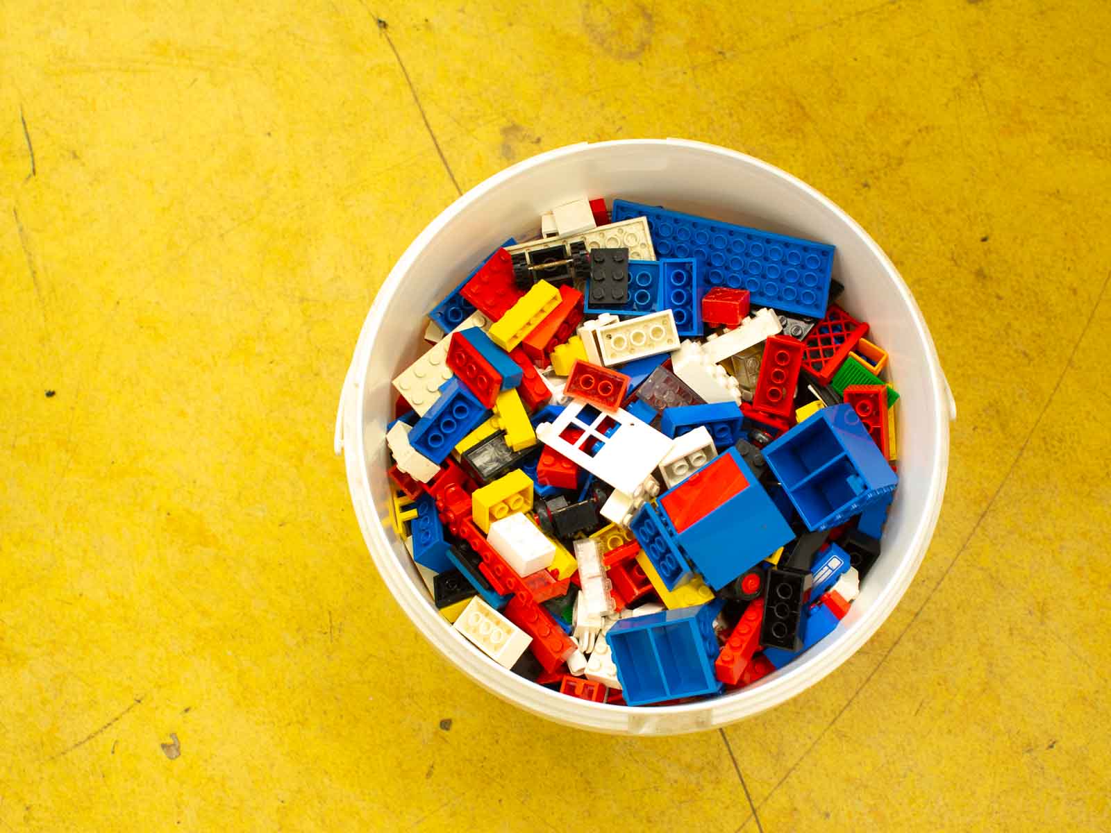 Colorful LEGO bricks in a white bucket inspire creativity and imaginative play in any setting.