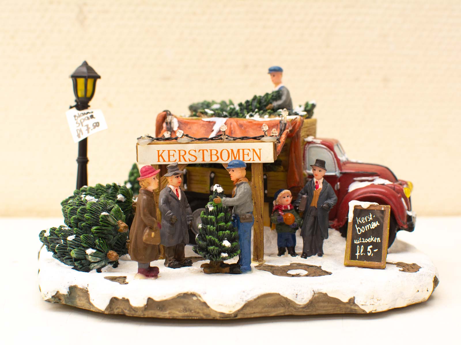 Festive miniature Christmas tree market scene with vintage figurines and snow-covered decorations.