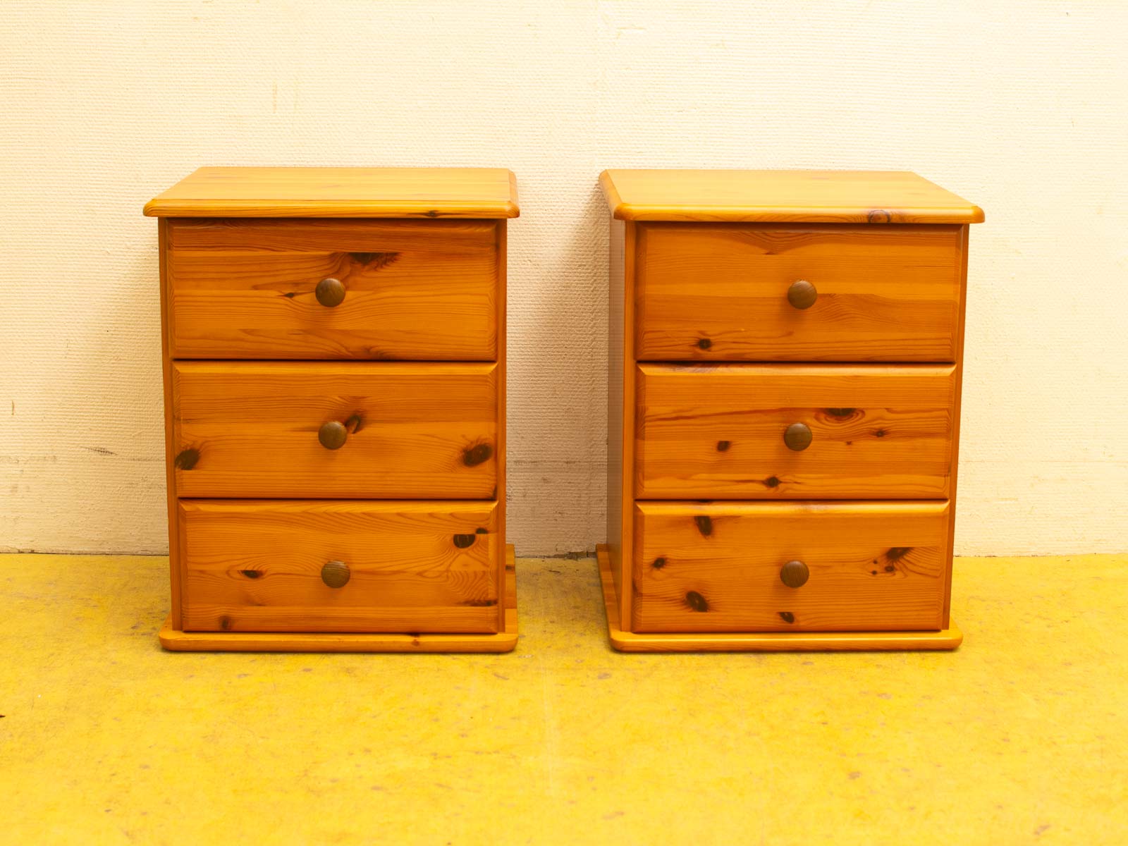 Rustic wooden nightstands with three drawers, perfect for a cozy bedroom setting.