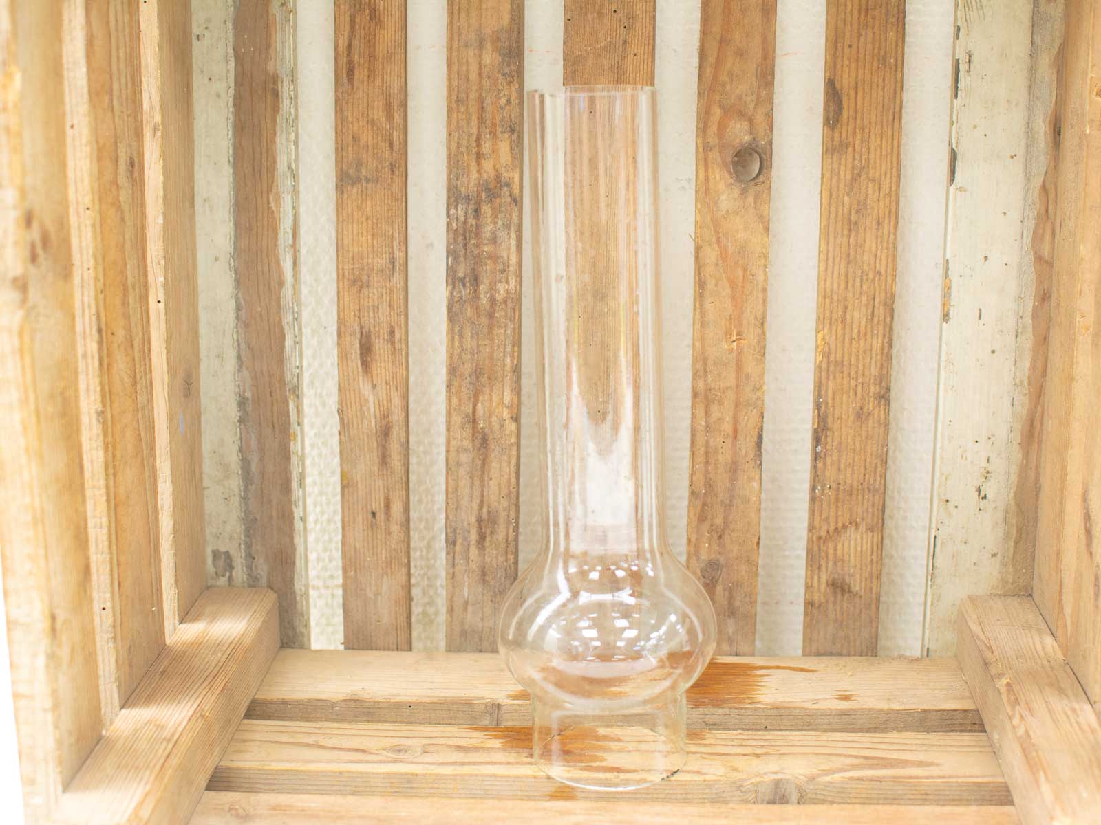 Elegant glass lamp chimney in a rustic wooden crate, perfect for vintage home decor.