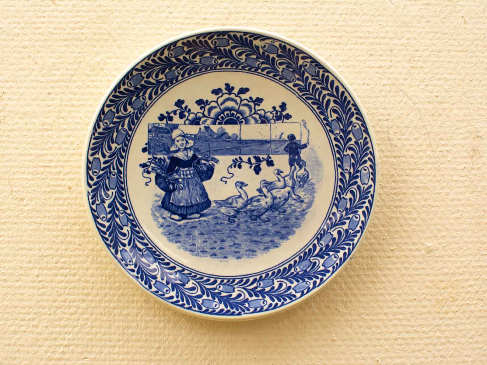 Vintage blue and white decorative plate showcasing a pastoral scene of rural life.