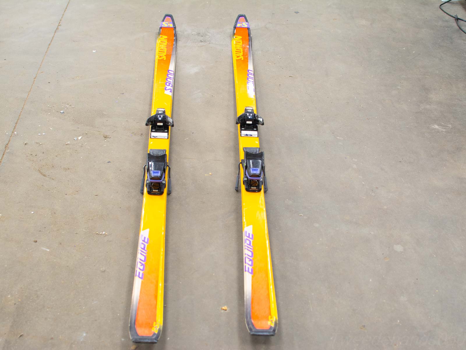 Bright yellow water skis with black bindings, ready for thrilling water sports adventures on concrete.