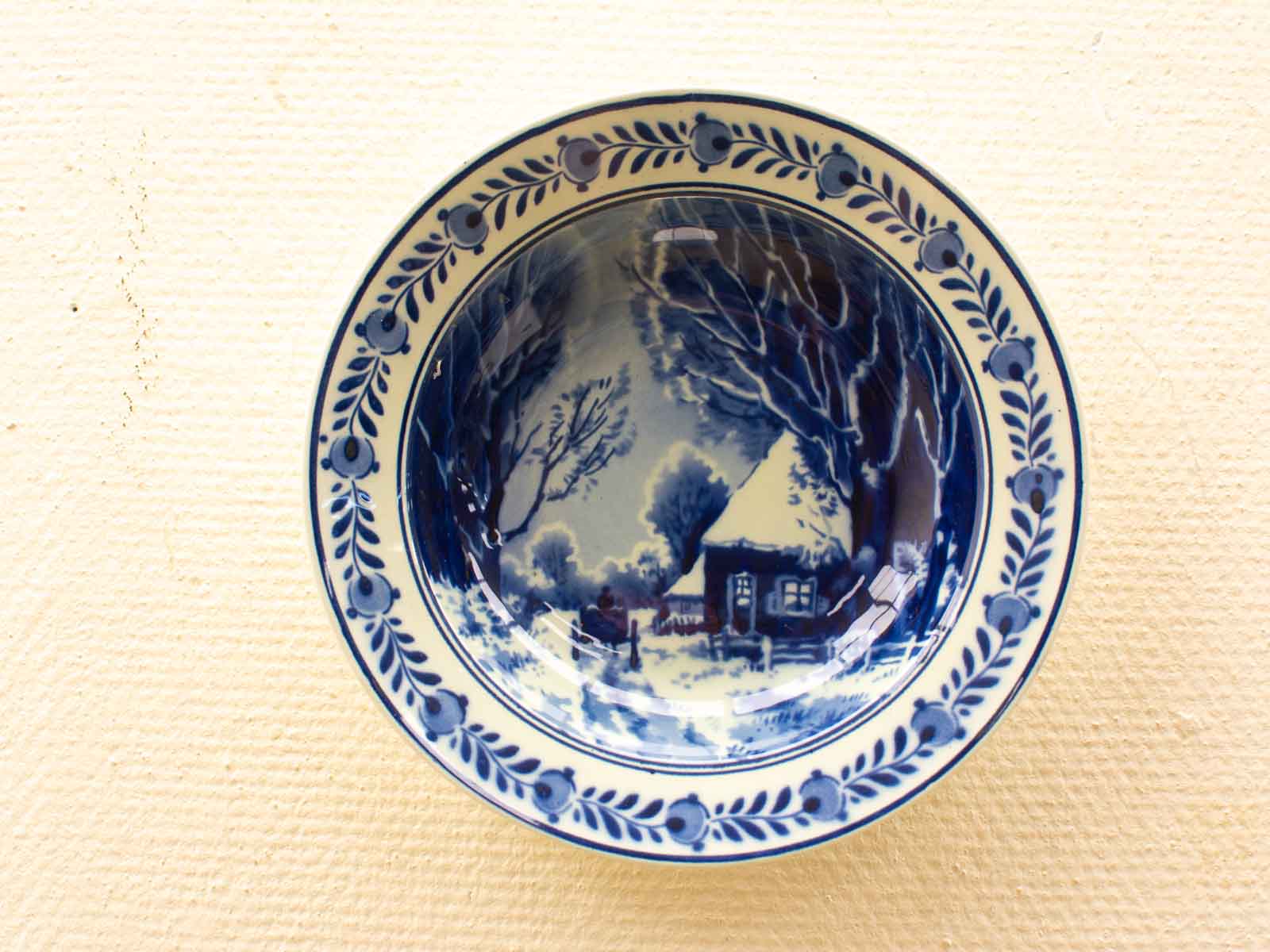 Elegant blue and white ceramic plate showcasing a tranquil winter landscape with a cozy home.