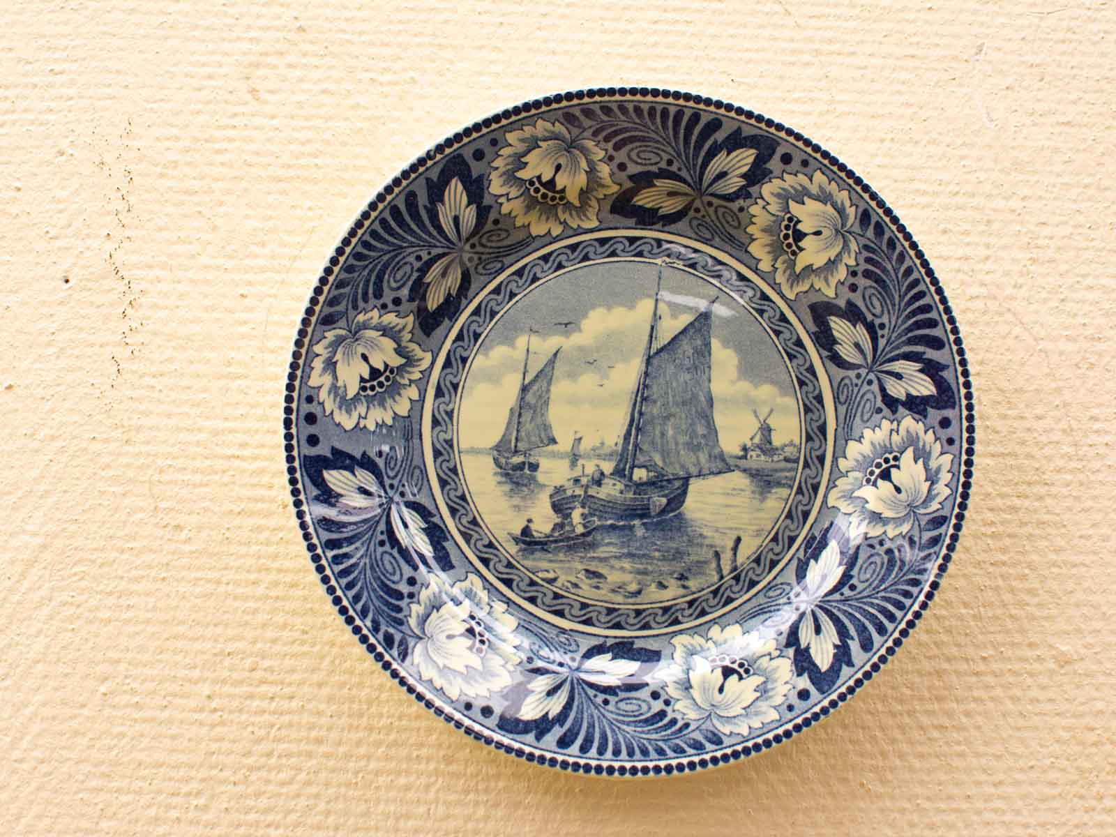 Elegant blue and white decorative plate featuring a serene nautical scene with sailing boats.