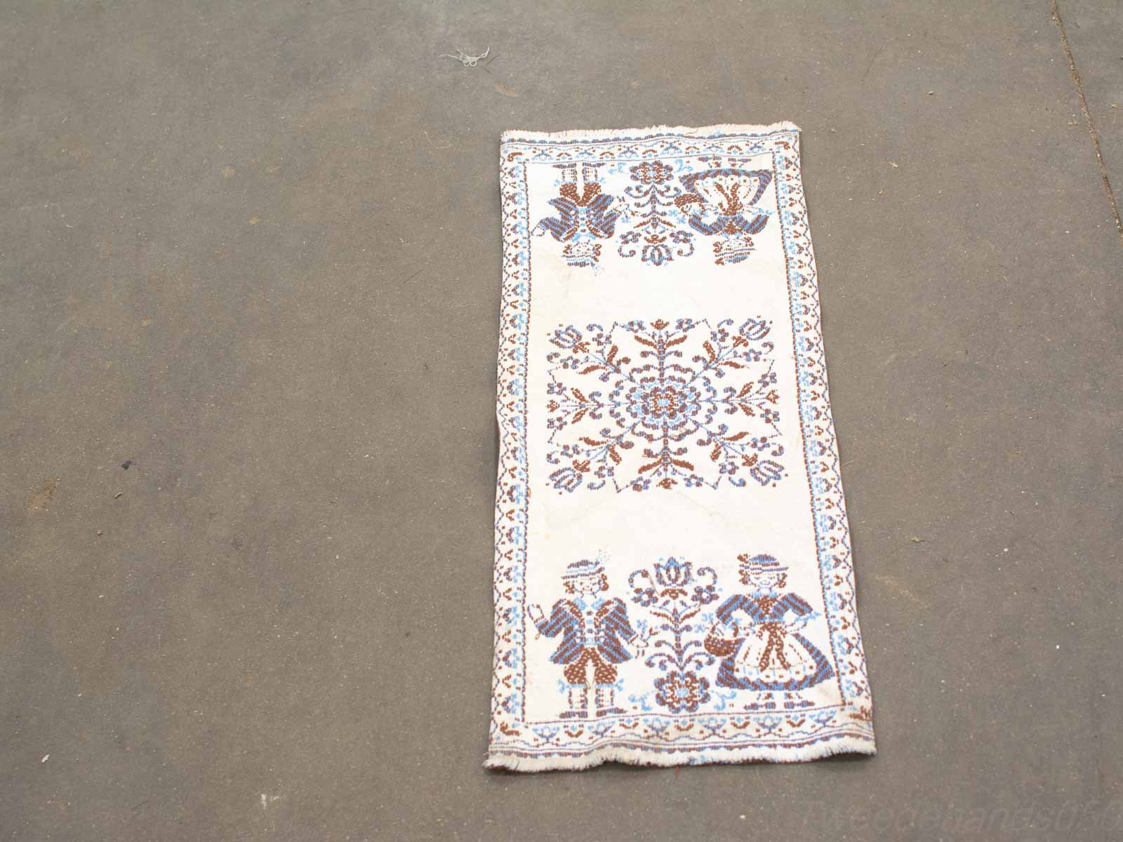 Elegant vintage rug with floral design and traditional figures in rich brown and blue tones.