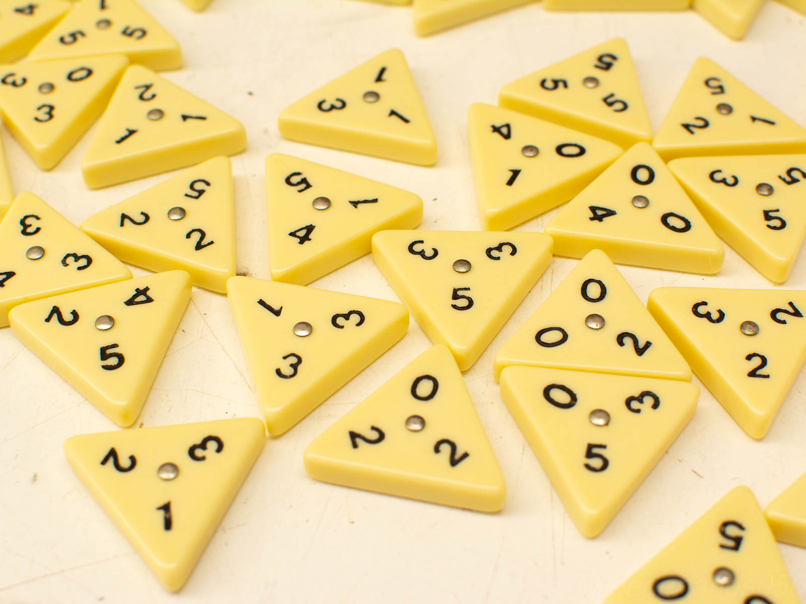 Pastel yellow triangular game pieces with numbers, reflecting a playful strategy game in progress.