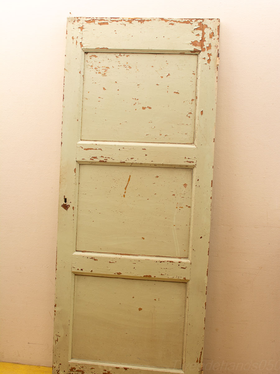 Weathered green vintage door against a soft backdrop with a vibrant yellow ground.