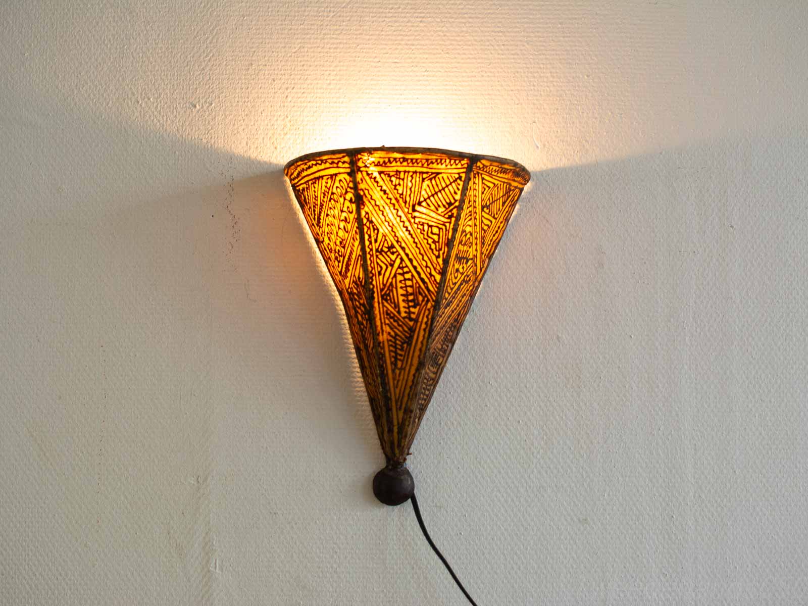 Elegant cone-shaped wall lamp with geometric patterns and warm light for inviting ambiance.