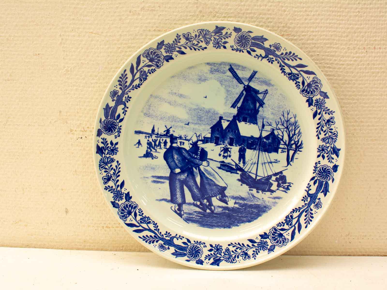 Winter scene decorative plate featuring couple, windmill, and nostalgic blue and white design.