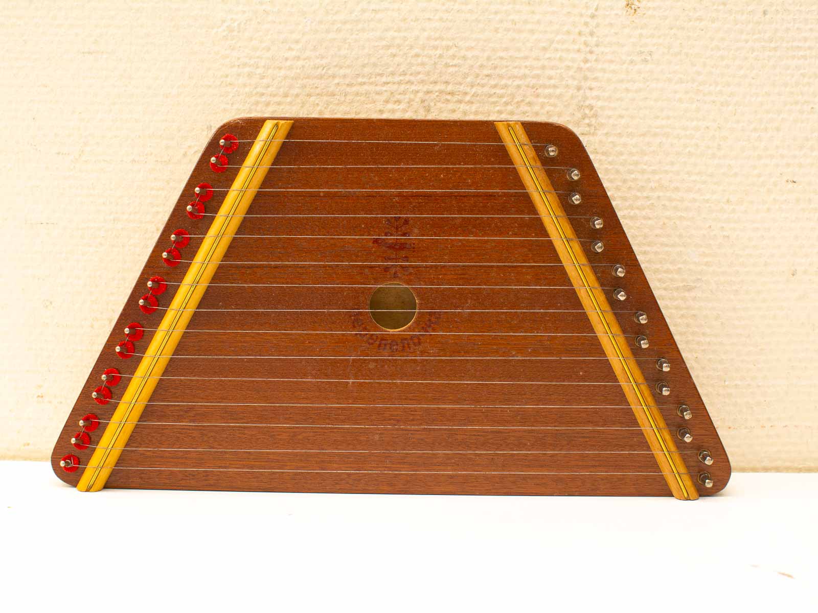 Vintage triangular wooden zither with red tuning pegs and elegant craftsmanship.