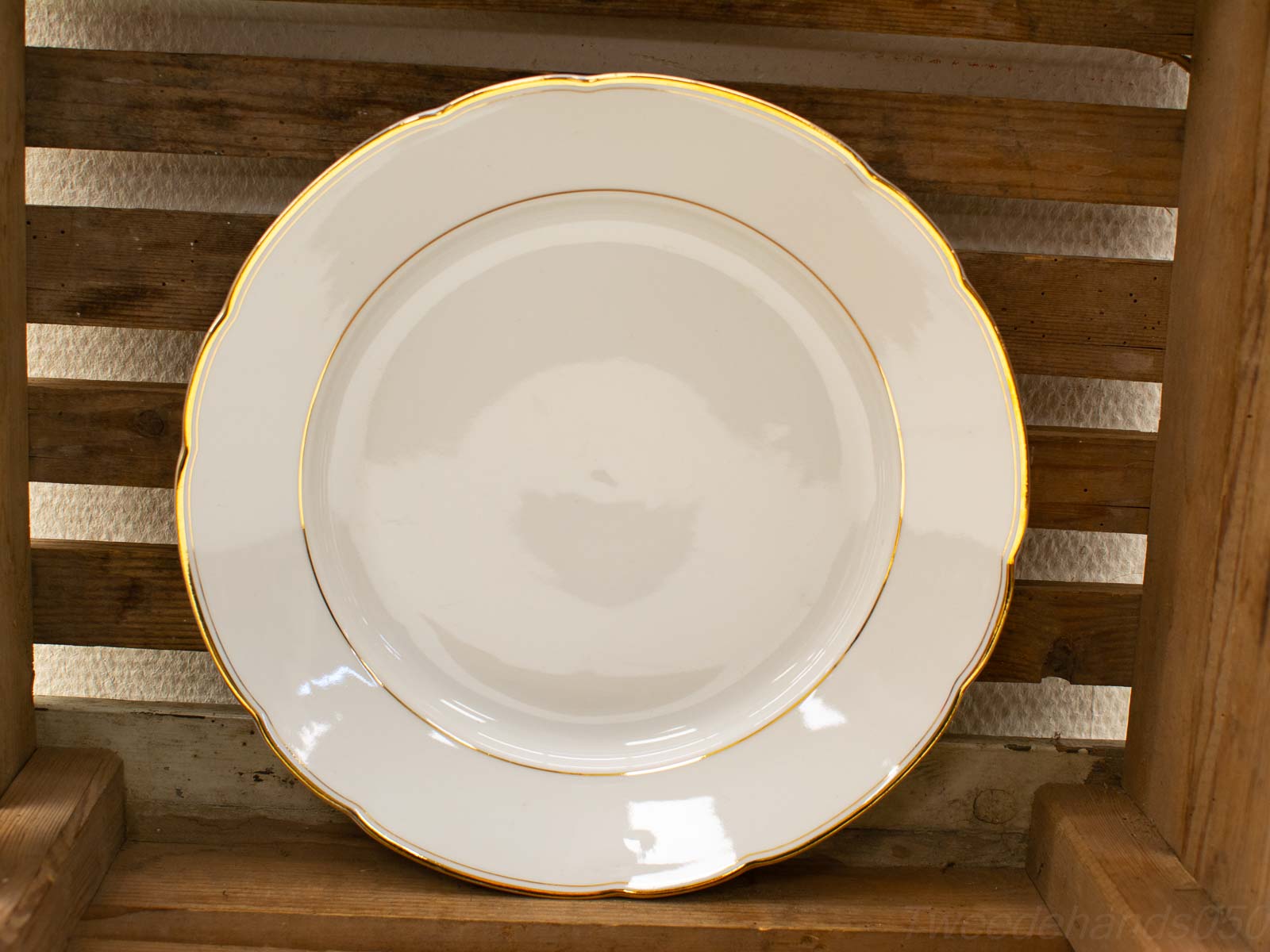 Elegant white plate with gold rim on rustic wooden surface, perfect for dining and decor.