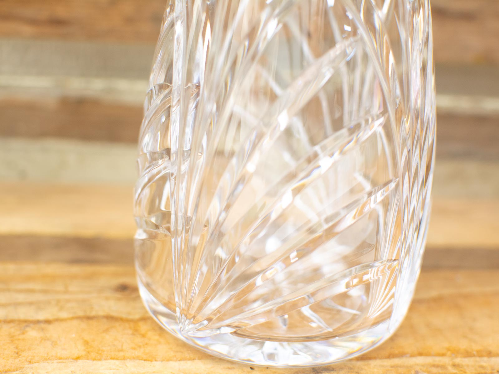 Elegant cut crystal glass vase showcasing intricate natural patterns on a warm wooden surface.