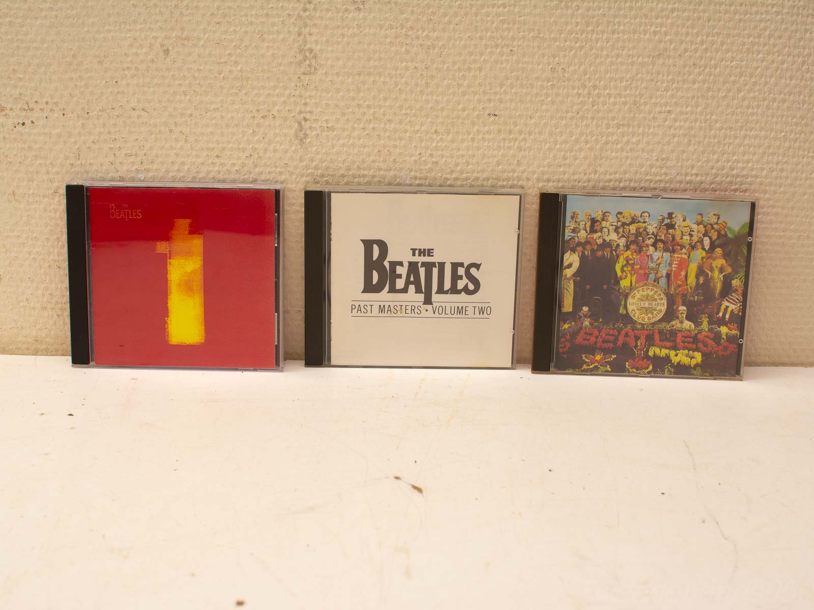 Drie tweedehands Beatles CDs met iconische hoezen, perfect voor elke muziekliefhebber.