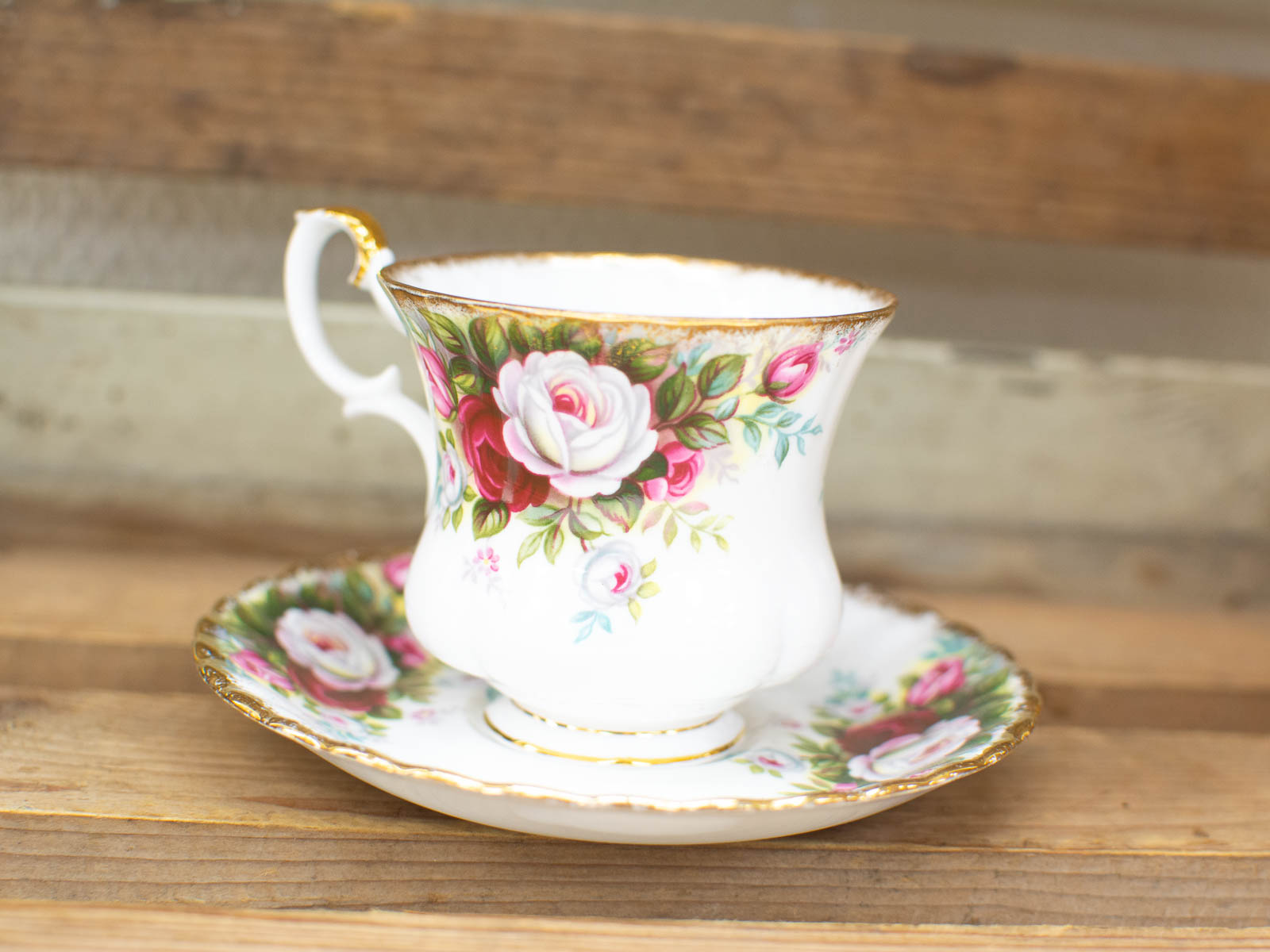 Elegant vintage tea cup and saucer set with floral design on rustic wooden background.