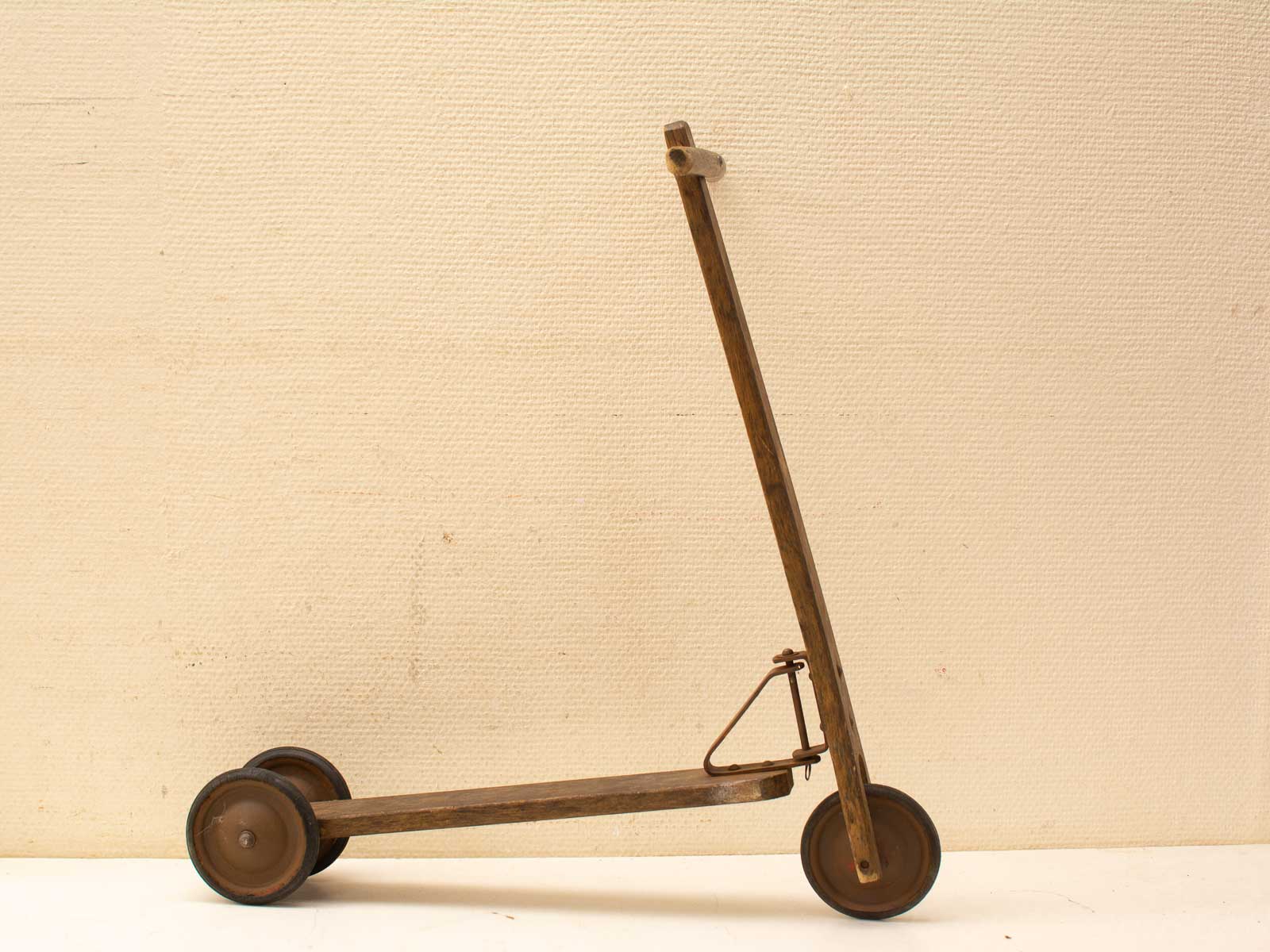 Vintage houten scooter tegen een neutrale achtergrond, perfect voor nostalgische liefhebbers van tweedehands spullen.