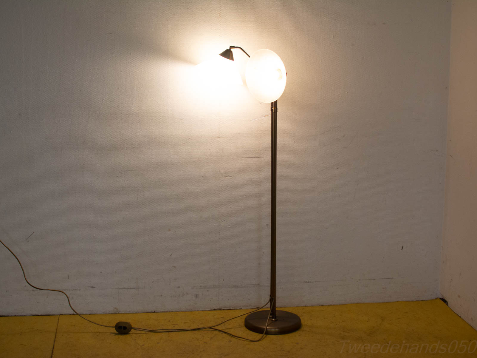 Moderne vloerlamp met dubbele lichtbronnen tegen een textuur muur, ideaal voor elke leefruimte.