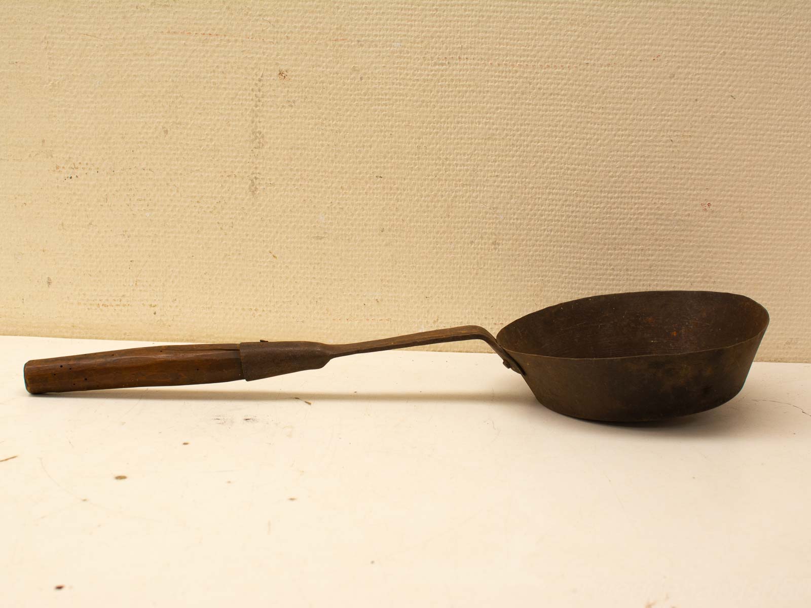 Vintage ladle with a rustic wooden handle, perfect for traditional cooking and kitchen decor.