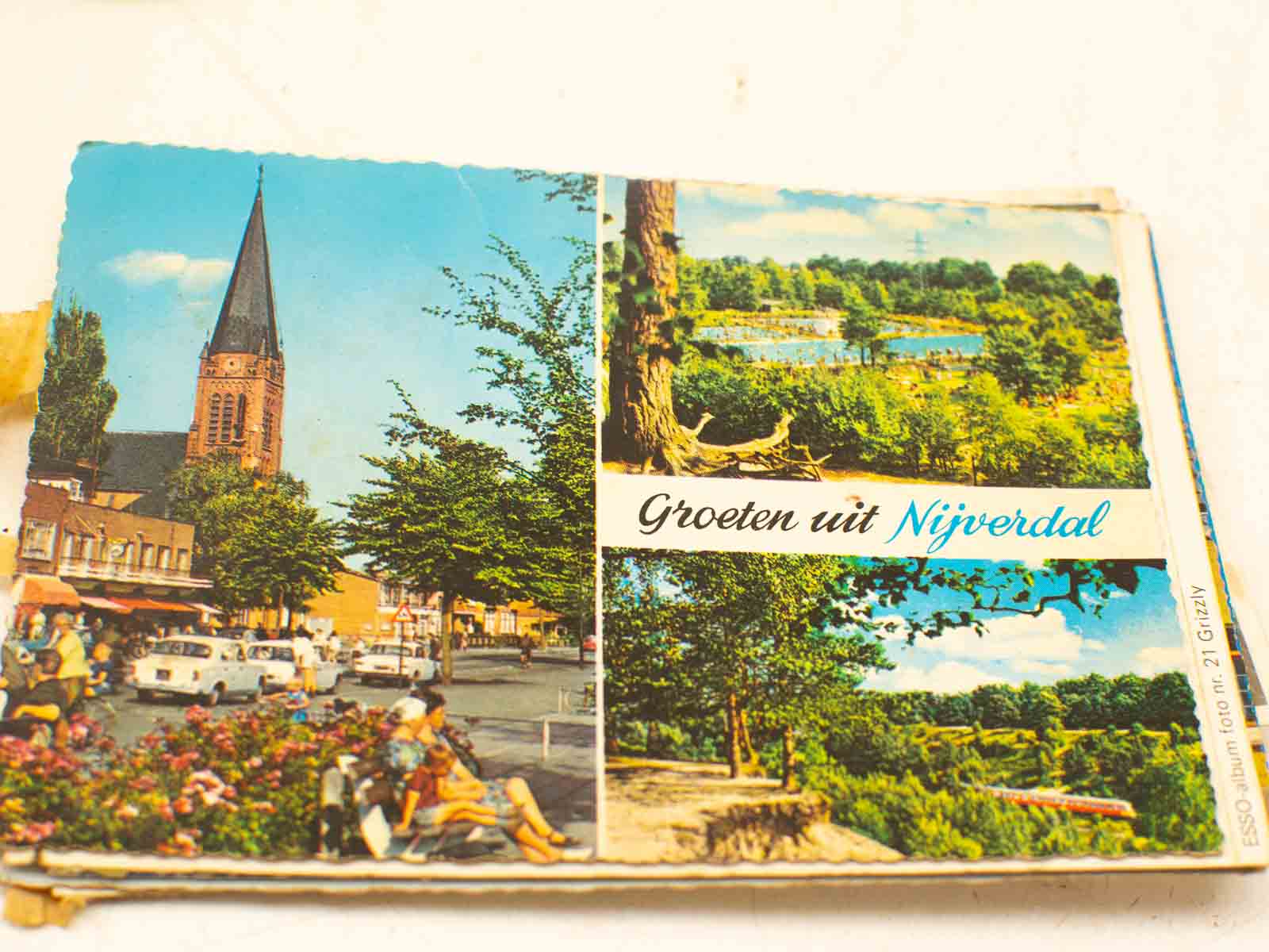 Vintage postcard of Nijverdal showcasing a church and scenic lake, inviting exploration.