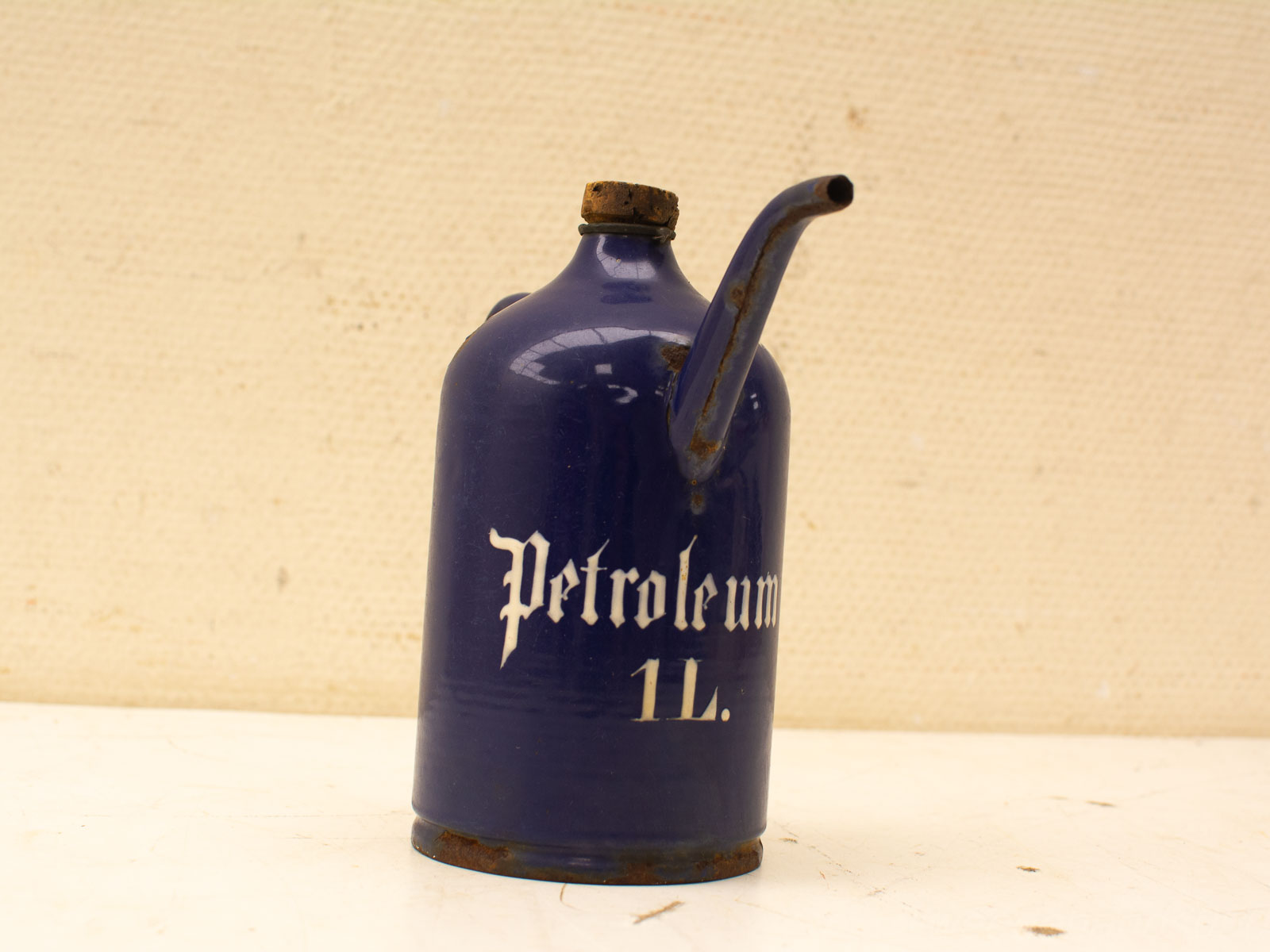 Vintage cobalt blue petroleum canister with gothic lettering and cork cap, showing signs of wear.