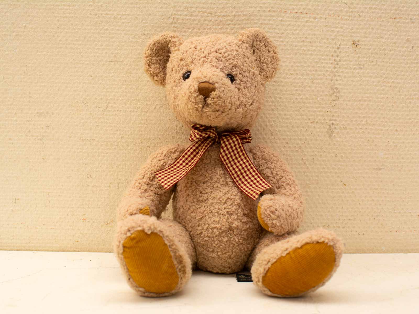 Schattige vintage teddybeer met geruite strik, perfect voor kinderen en nostalgische decoratie.