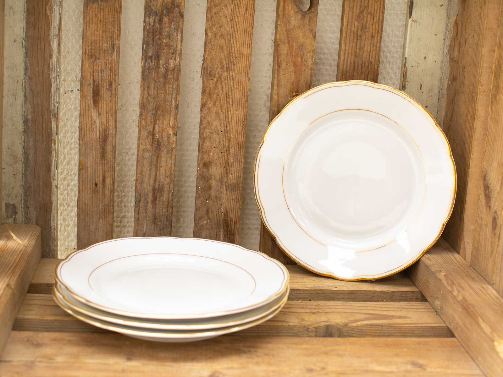 Elegant vintage plates on a rustic wooden table create a warm dining ambiance.