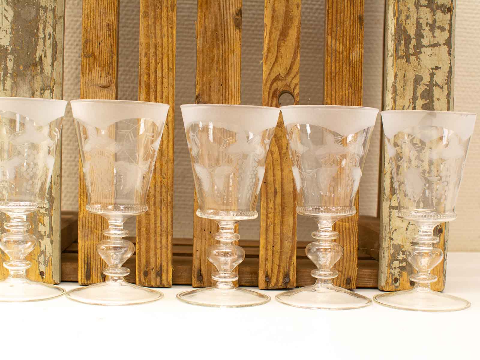 Exquisite etched glasses on rustic wood, showcasing elegance and artisanal craftsmanship in a charming display.