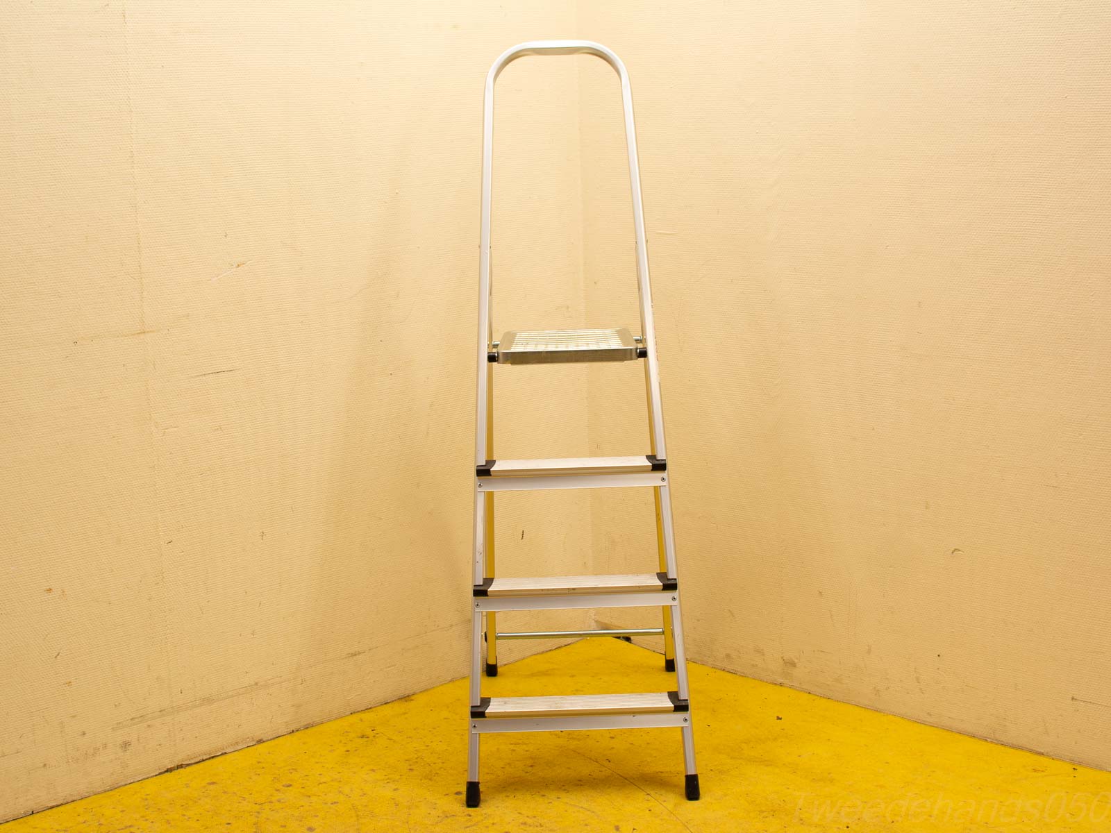 Sturdy aluminum ladder against a warm yellow wall, ideal for home and workspace tasks.