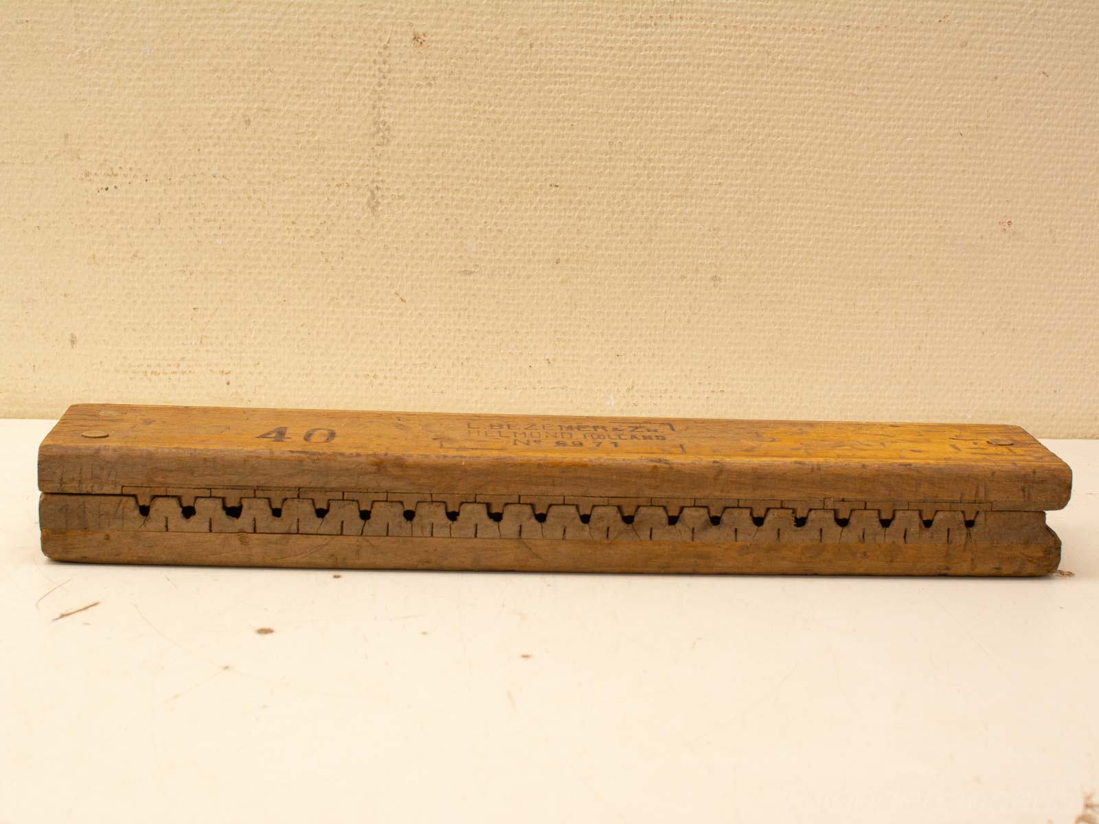 Antique wooden measuring tool with notches, showcasing rich patina and craftsmanship for woodworking enthusiasts.