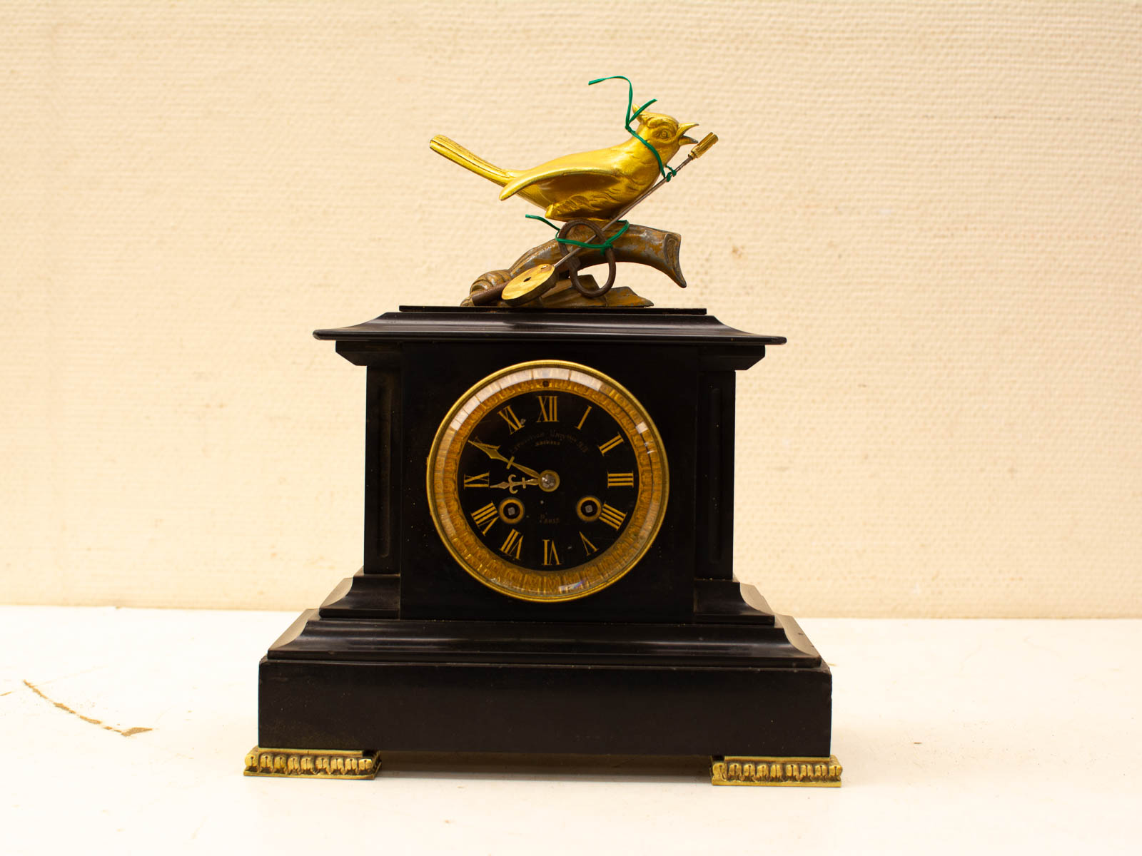 Elegant vintage bird clock with gold accents, Roman numerals, and intricate design features.