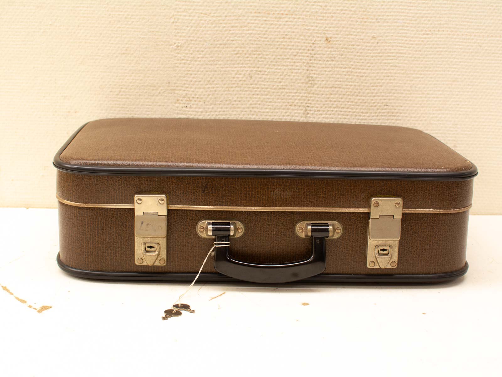 Classic vintage brown suitcase with metallic clasps and keys, evoking nostalgic travel memories.