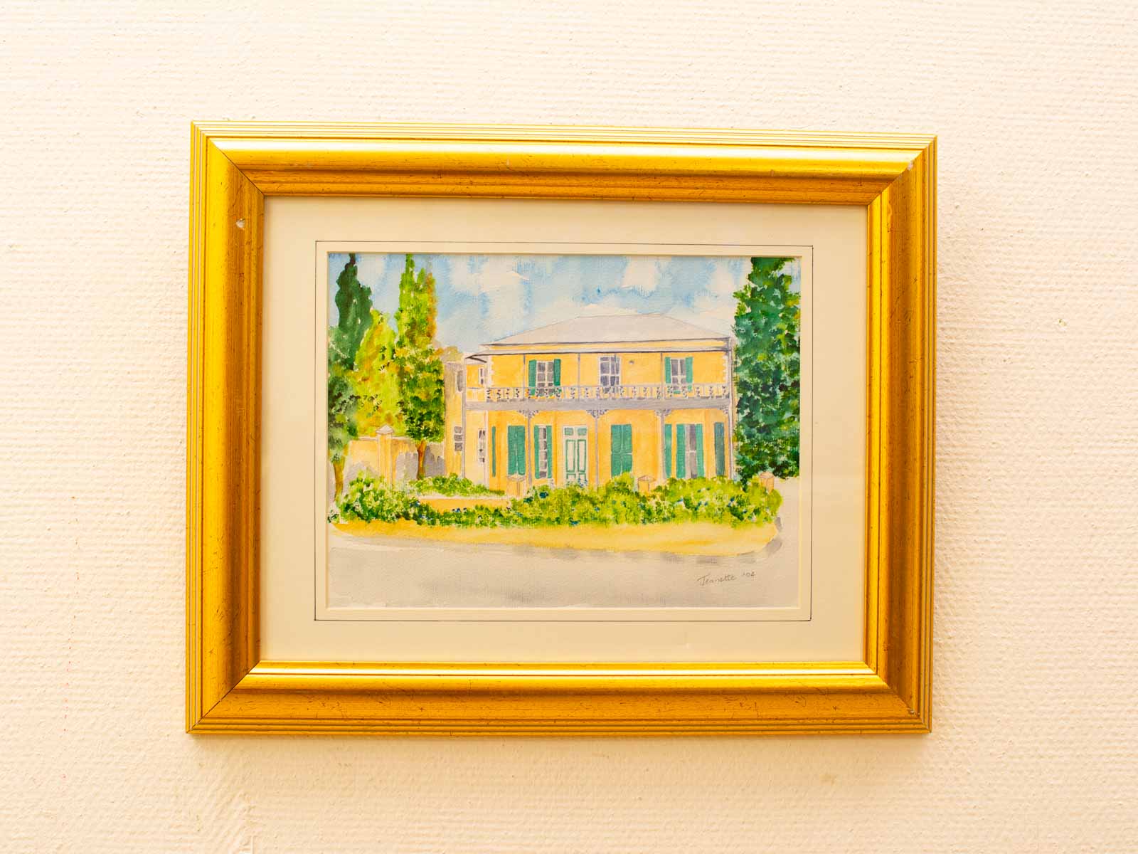 Charming watercolor painting of a yellow house with green shutters and a vibrant garden.