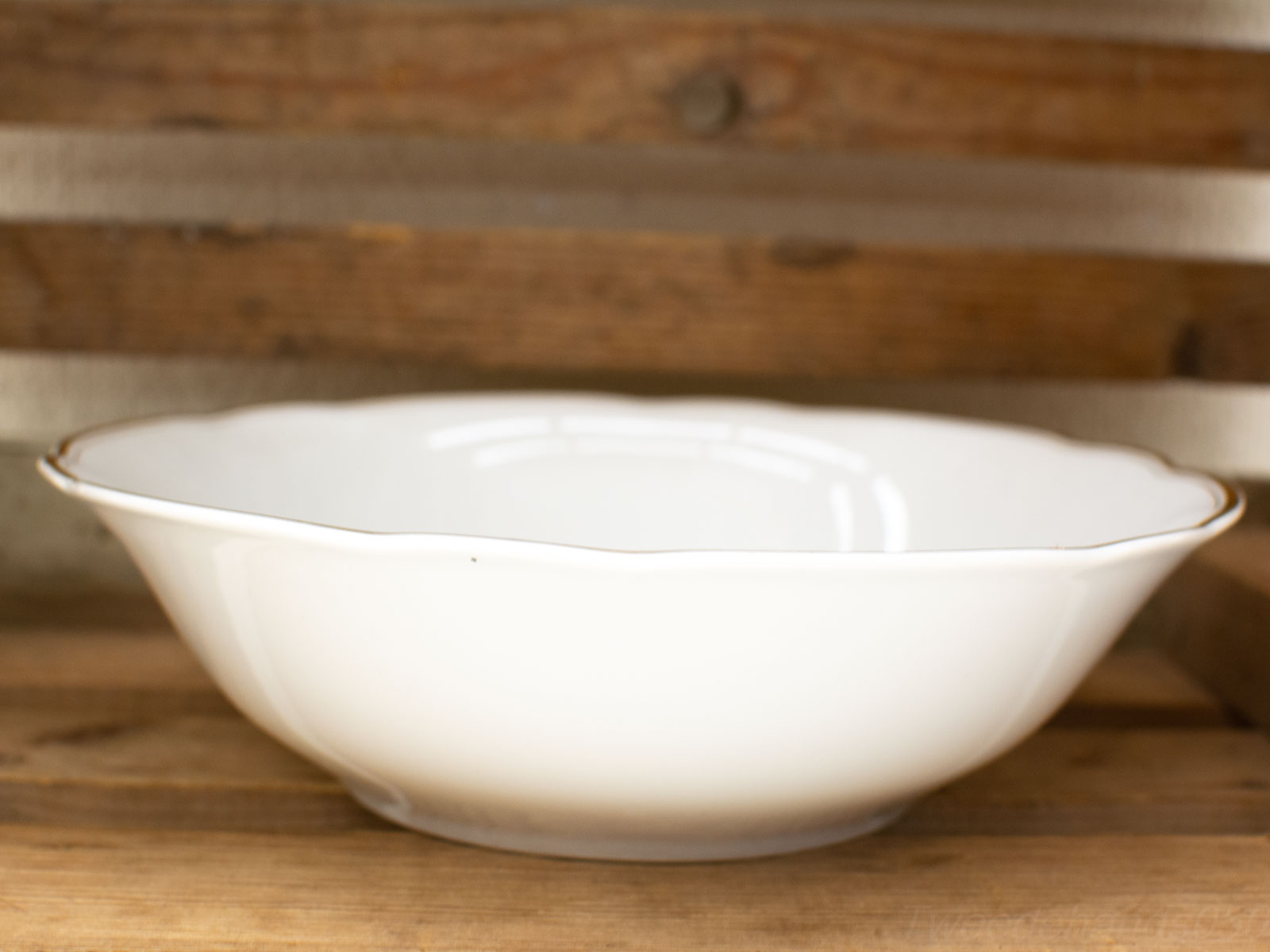 Elegant porcelain bowl with scalloped edge and gold rim, perfect for dining and decoration.