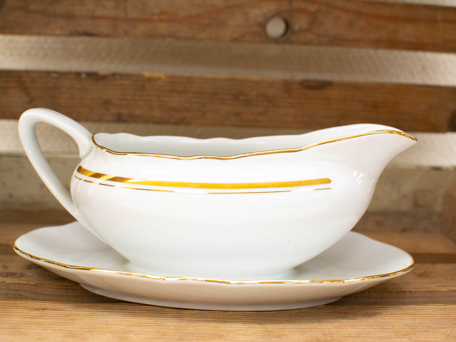 Elegant porcelain gravy boat with gold accents, perfect for decor or special occasions.