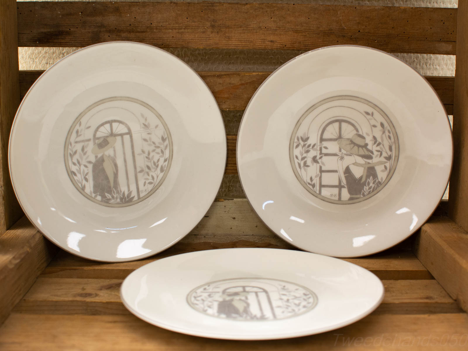 Decorative plates with serene figures on a rustic wooden surface, perfect for artistic display.