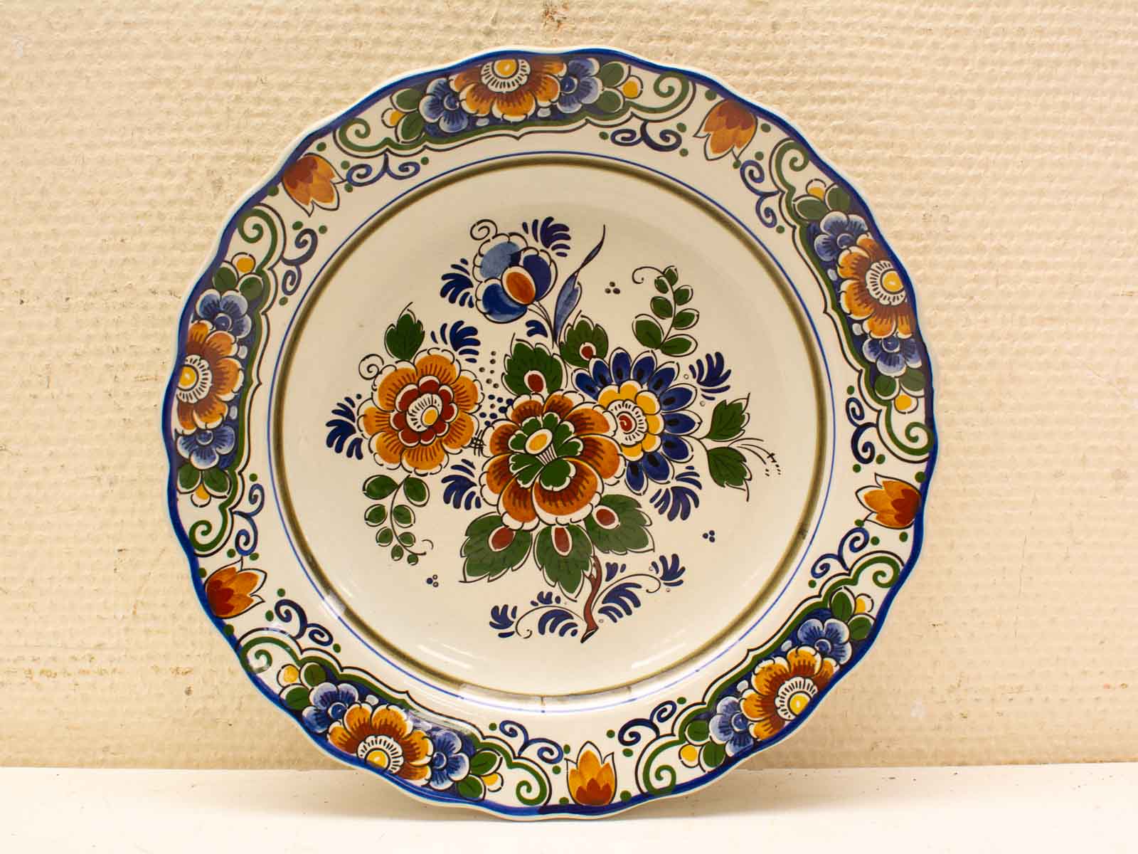 Vibrant hand-painted ceramic plate featuring colorful floral designs and a charming scalloped edge.