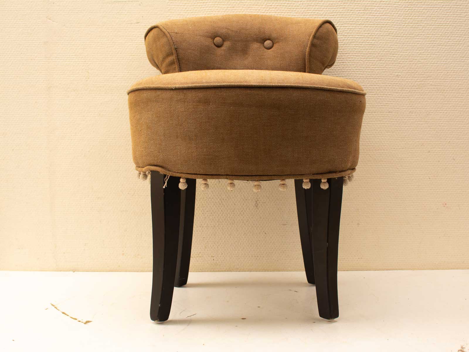 Cozy brown upholstered chair with playful pom-pom trim, perfect for stylish home interiors.