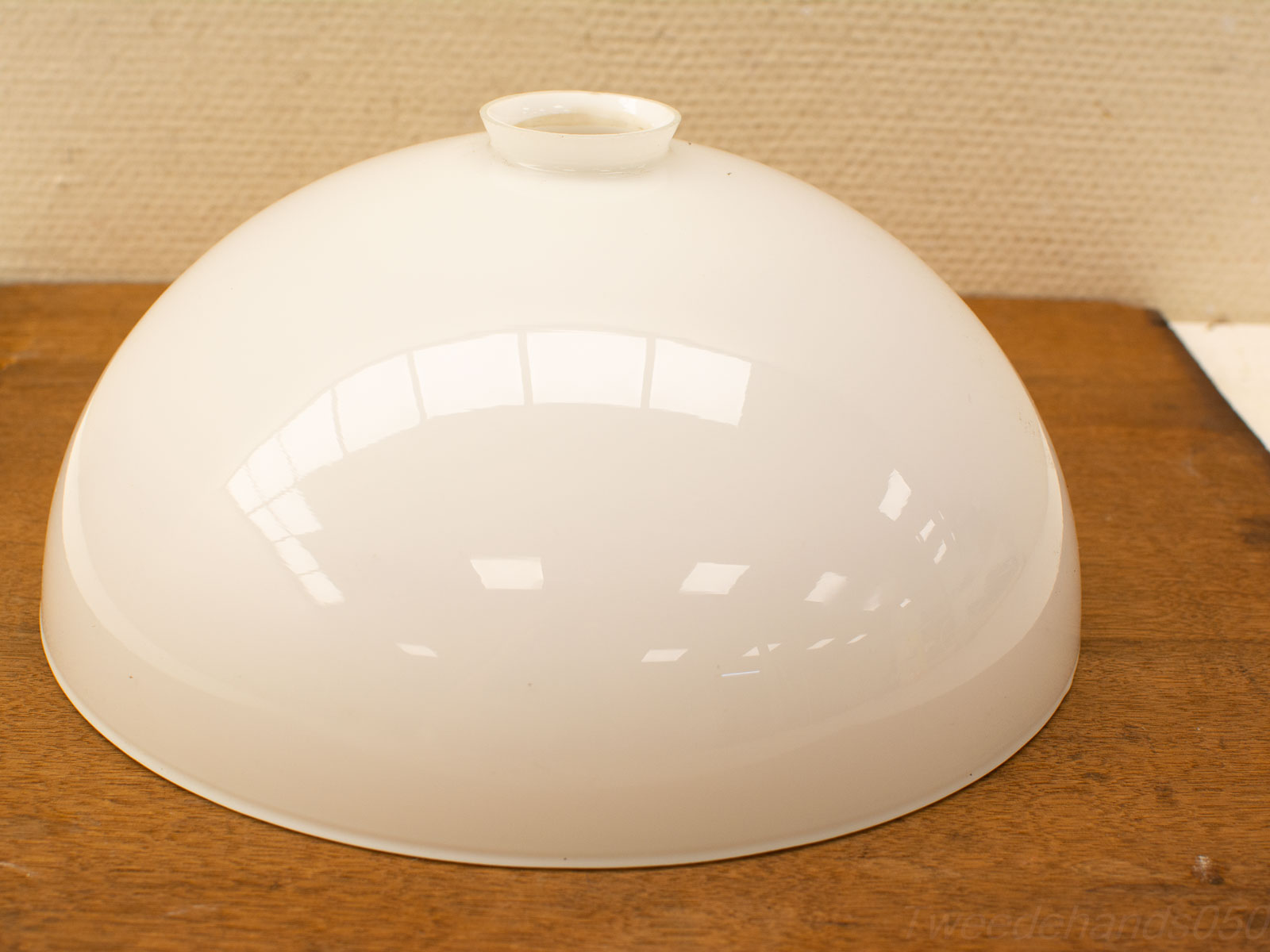 Glossy white ceramic cloche on rustic wood table, combining elegance with practicality for decor.