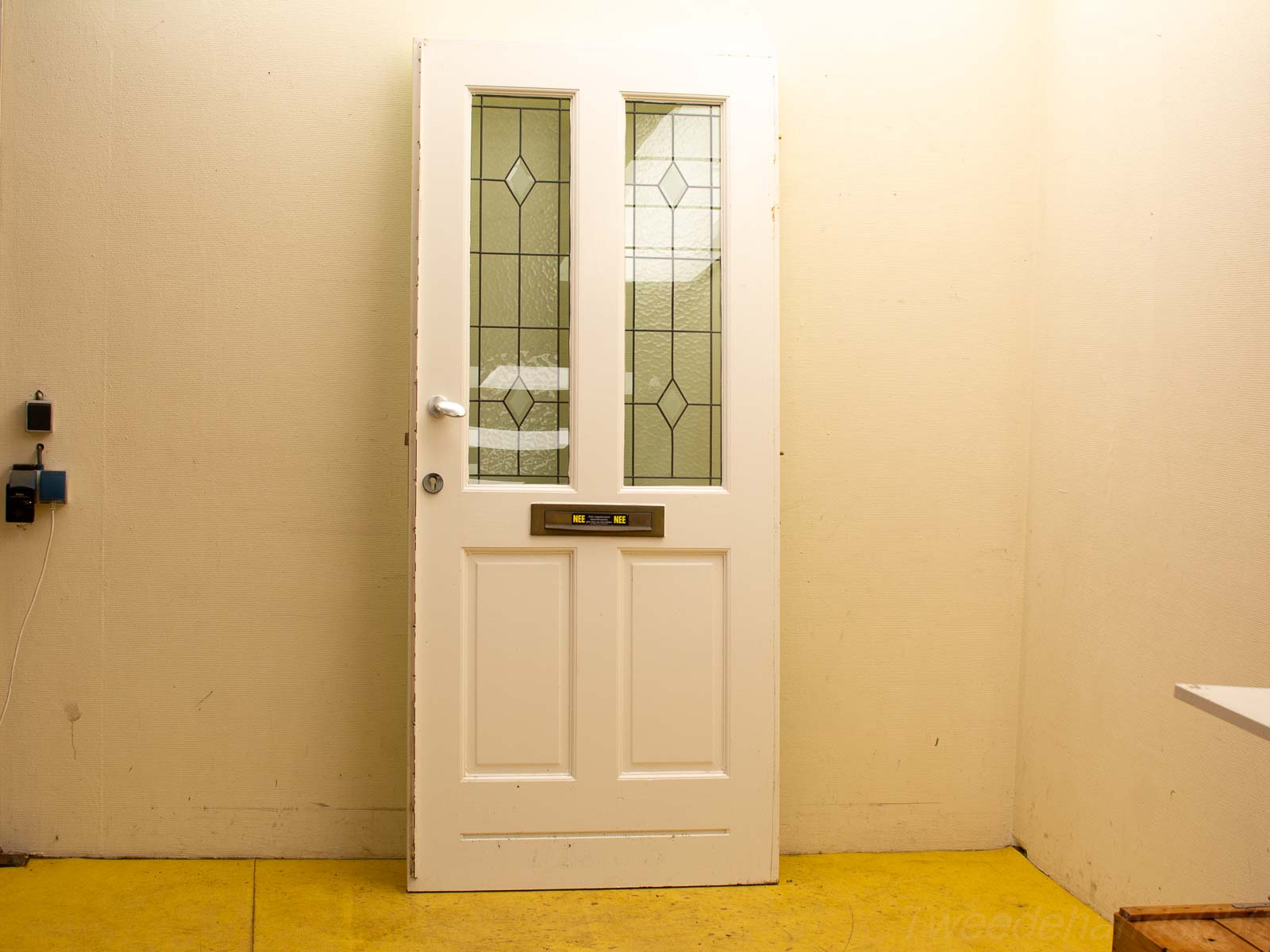 Elegant white door with diamond-patterned glass panels and bright yellow flooring.