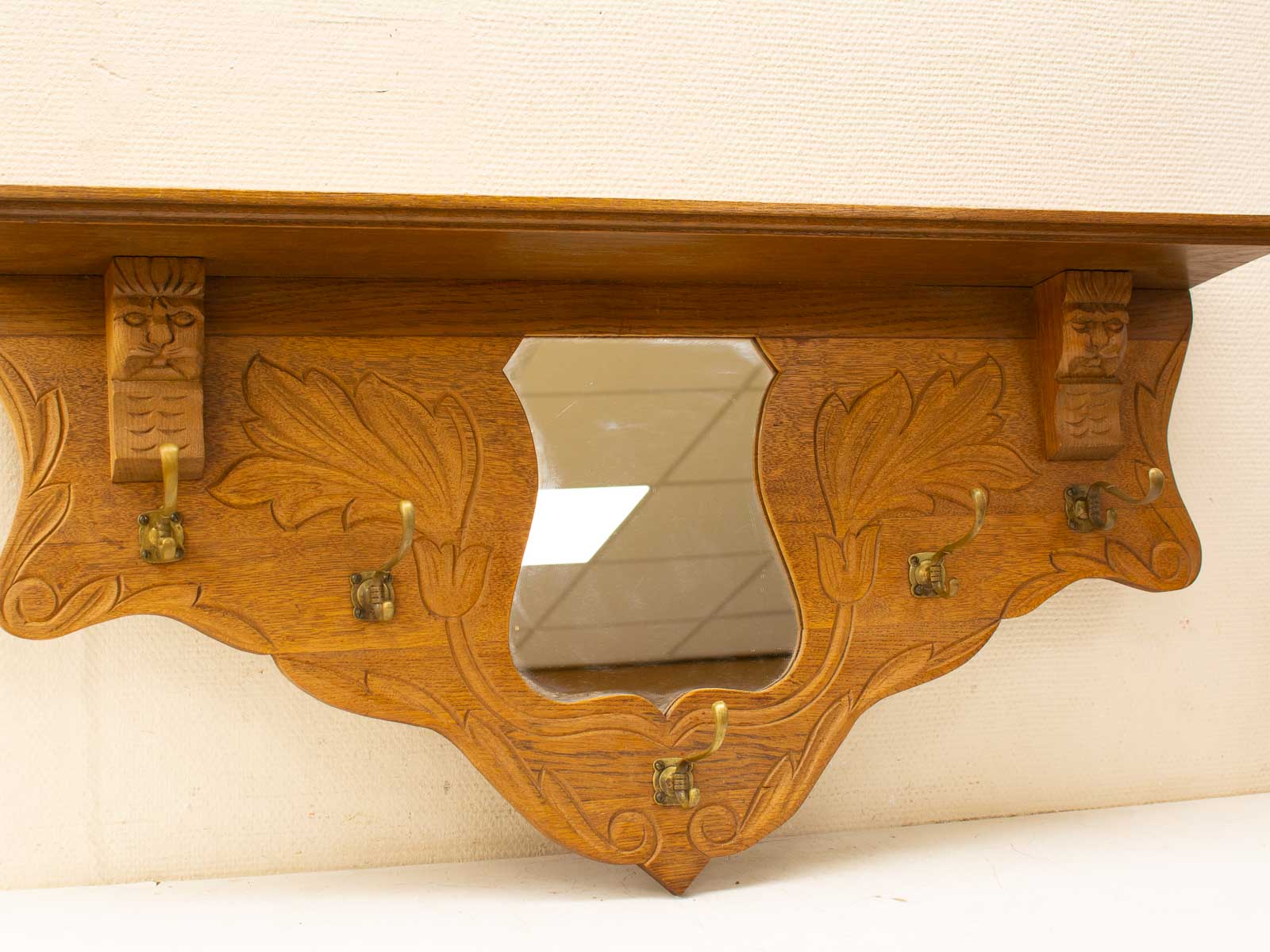 Elegant wooden shelf with mirror and carved faces, blending artistry and functionality in home decor.