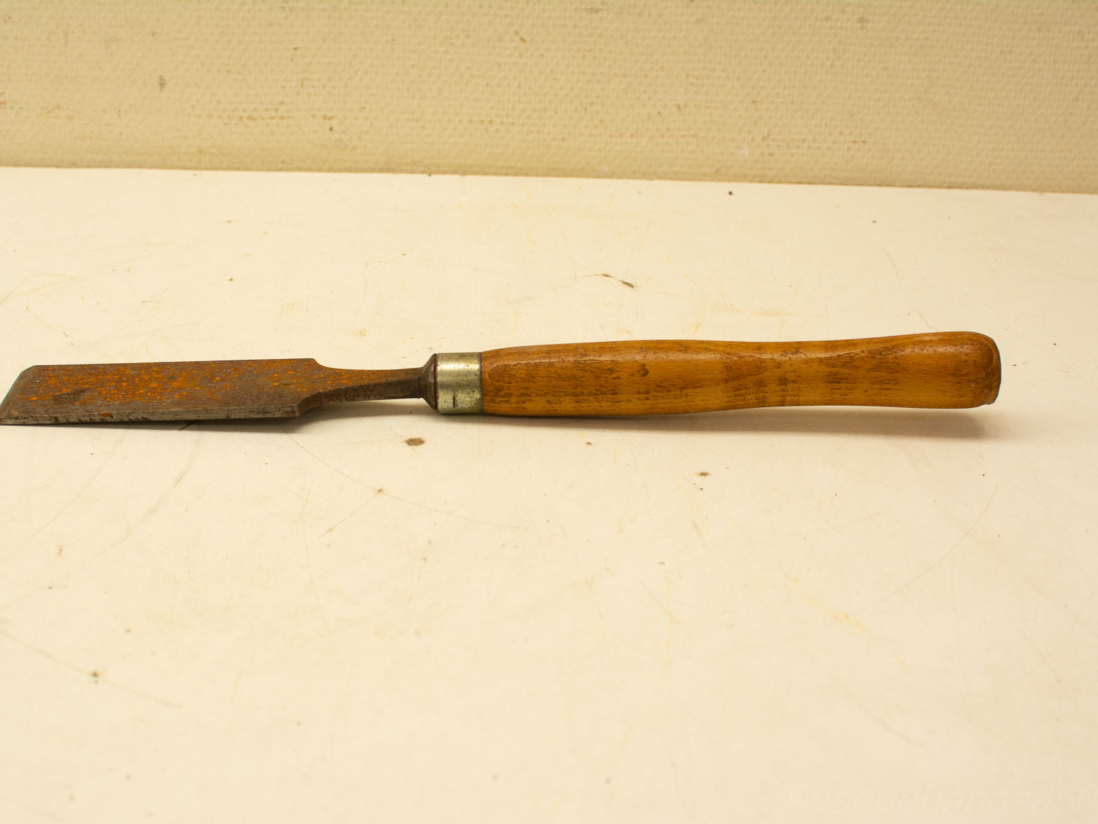 Rusty vintage woodworking chisel with polished wooden handle, ideal for detailed craftsmanship.