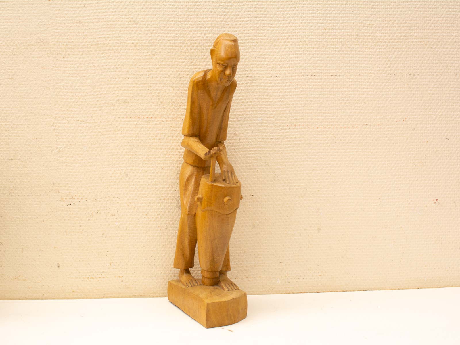 Elderly artisan carving a traditional drum in a beautifully crafted wooden sculpture.