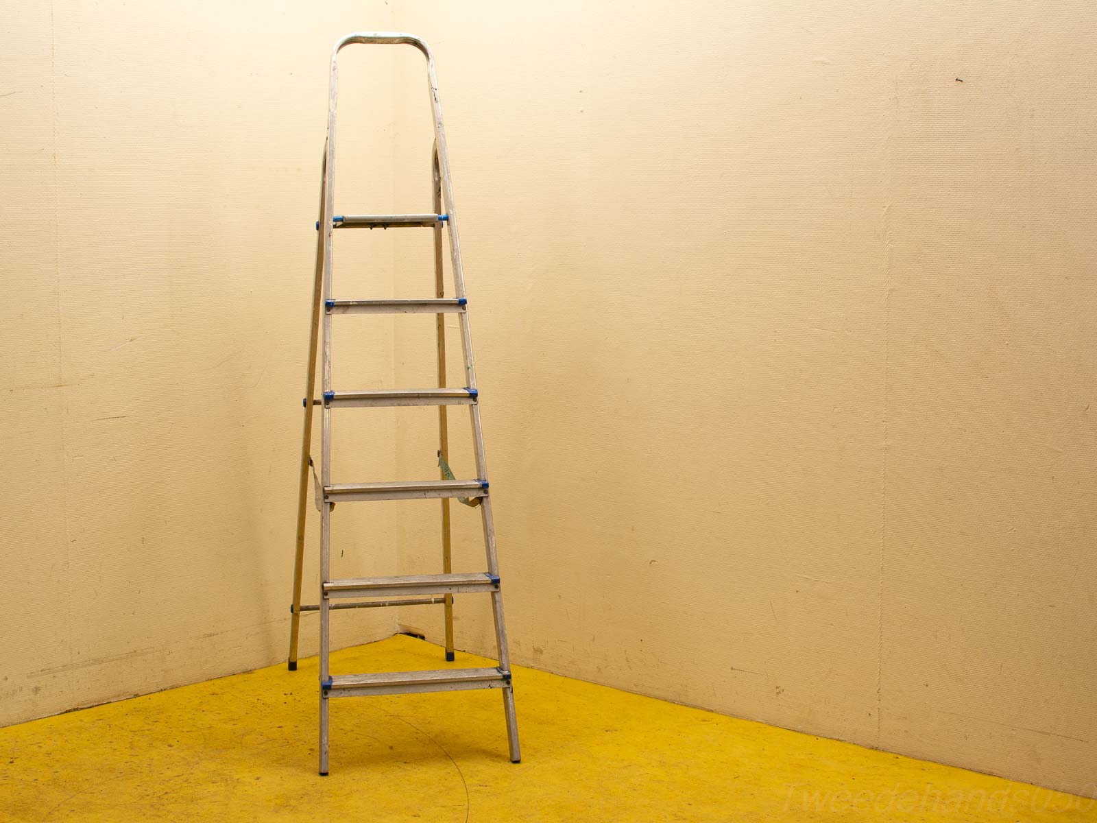 Sleek aluminum ladder in a cozy room corner with vibrant yellow floor and beige walls.