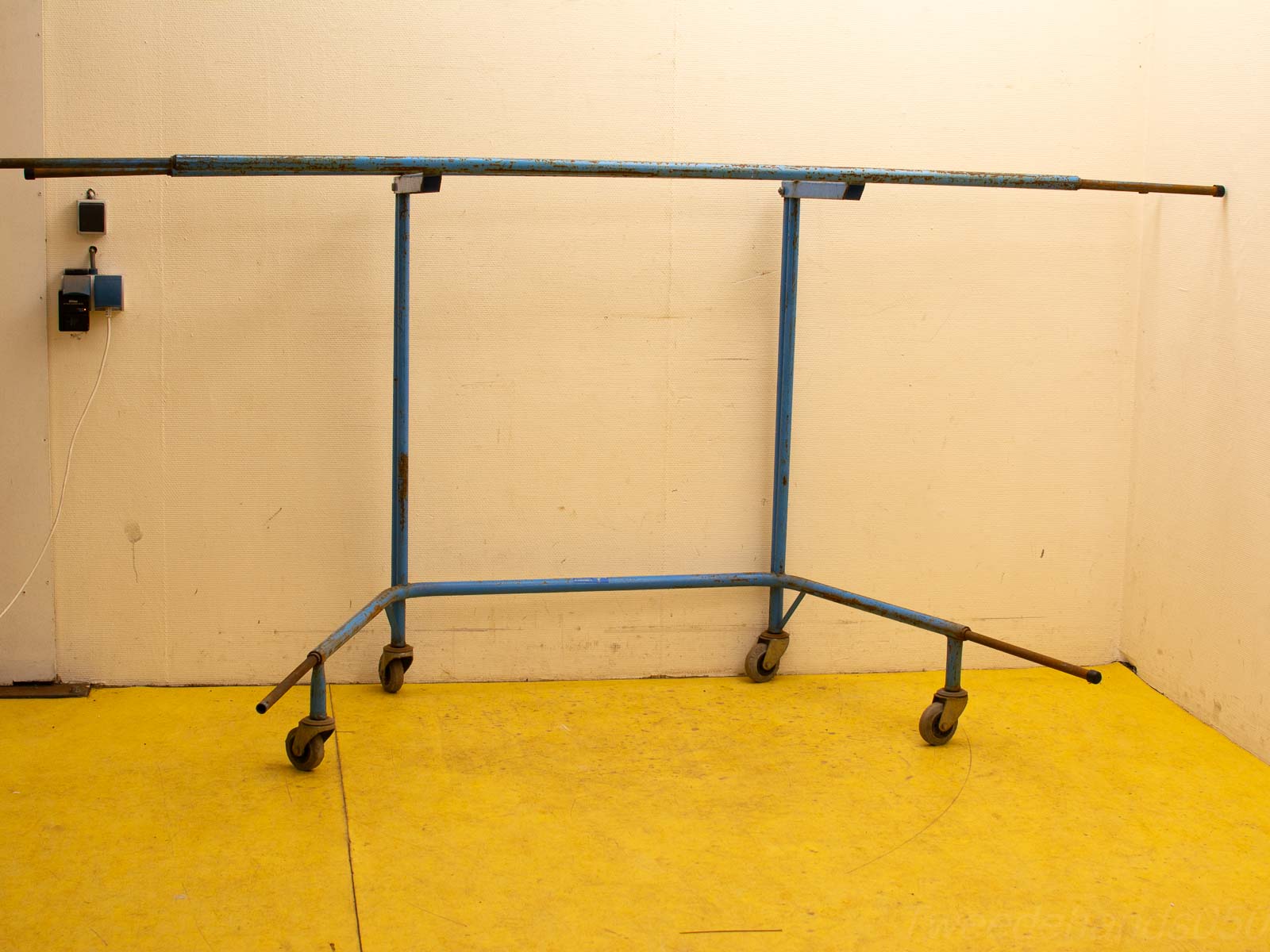 Blue industrial clothing rack with wheels, perfect for showcasing vintage or second-hand apparel.