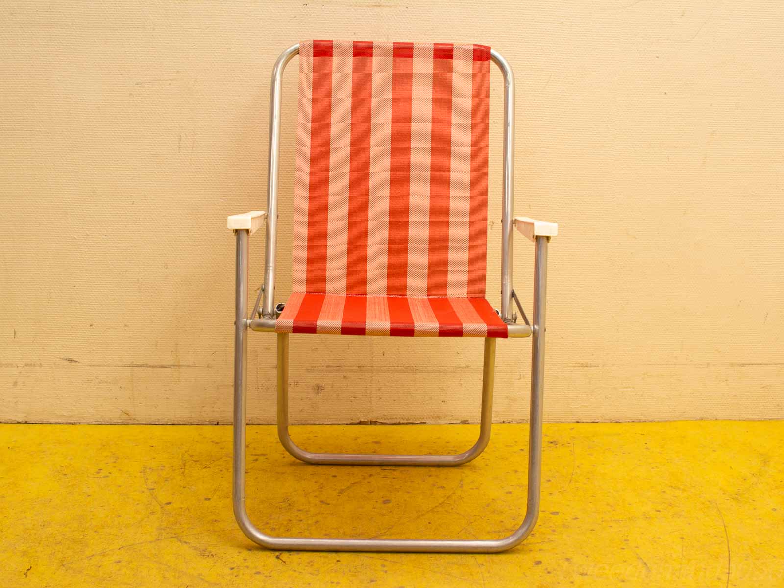 Vibrant striped outdoor chair with aluminum frame and wooden armrests for comfort and style.